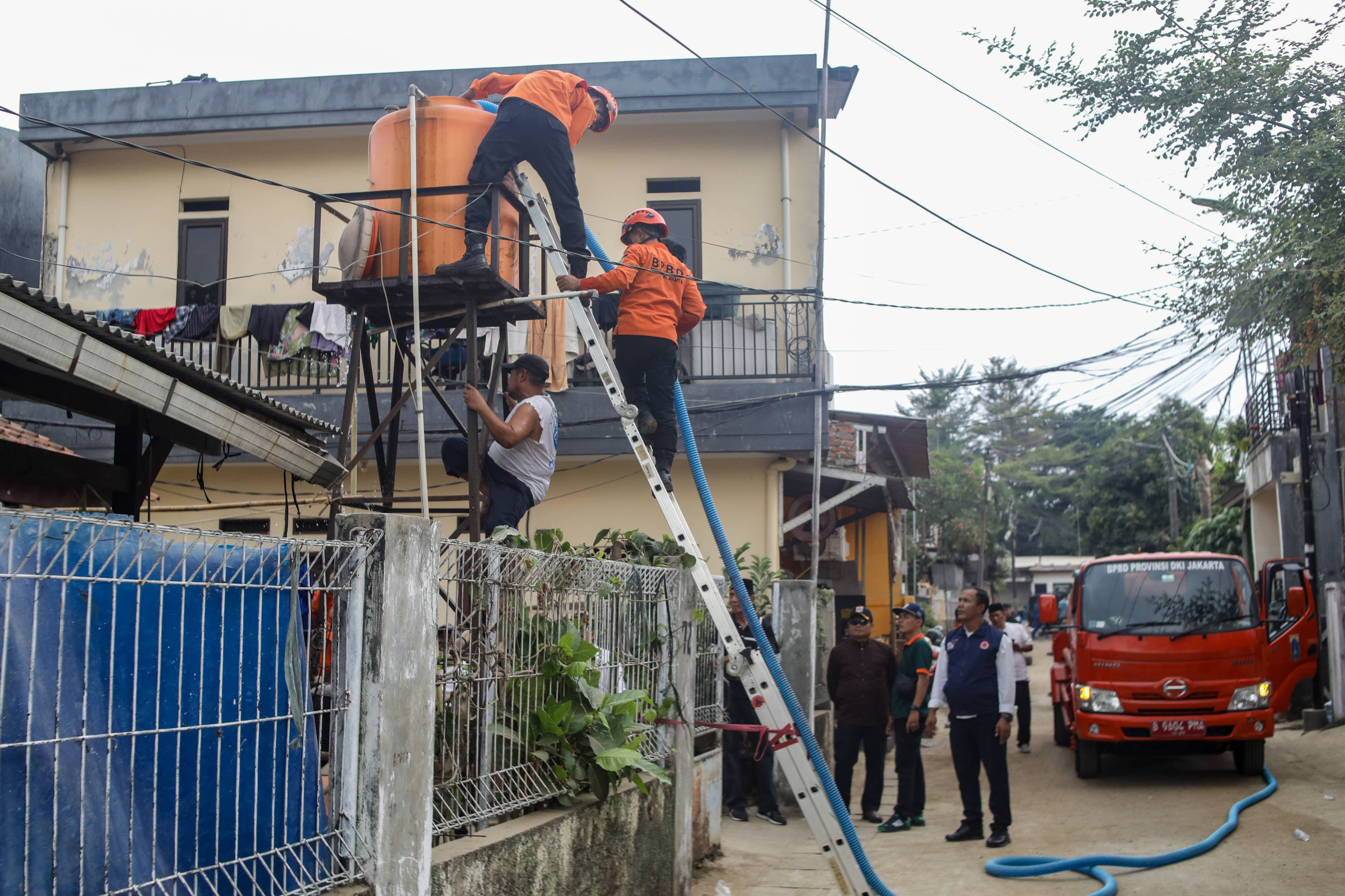 Personel BPBD Jakarta Selatan mengisi air ke dalam wadah milik warga yang terdampak kekeringan di Lenteng Agung, Jakarta, Jumat (18/9/2026). AKURAT.CO/Endra Prakoso