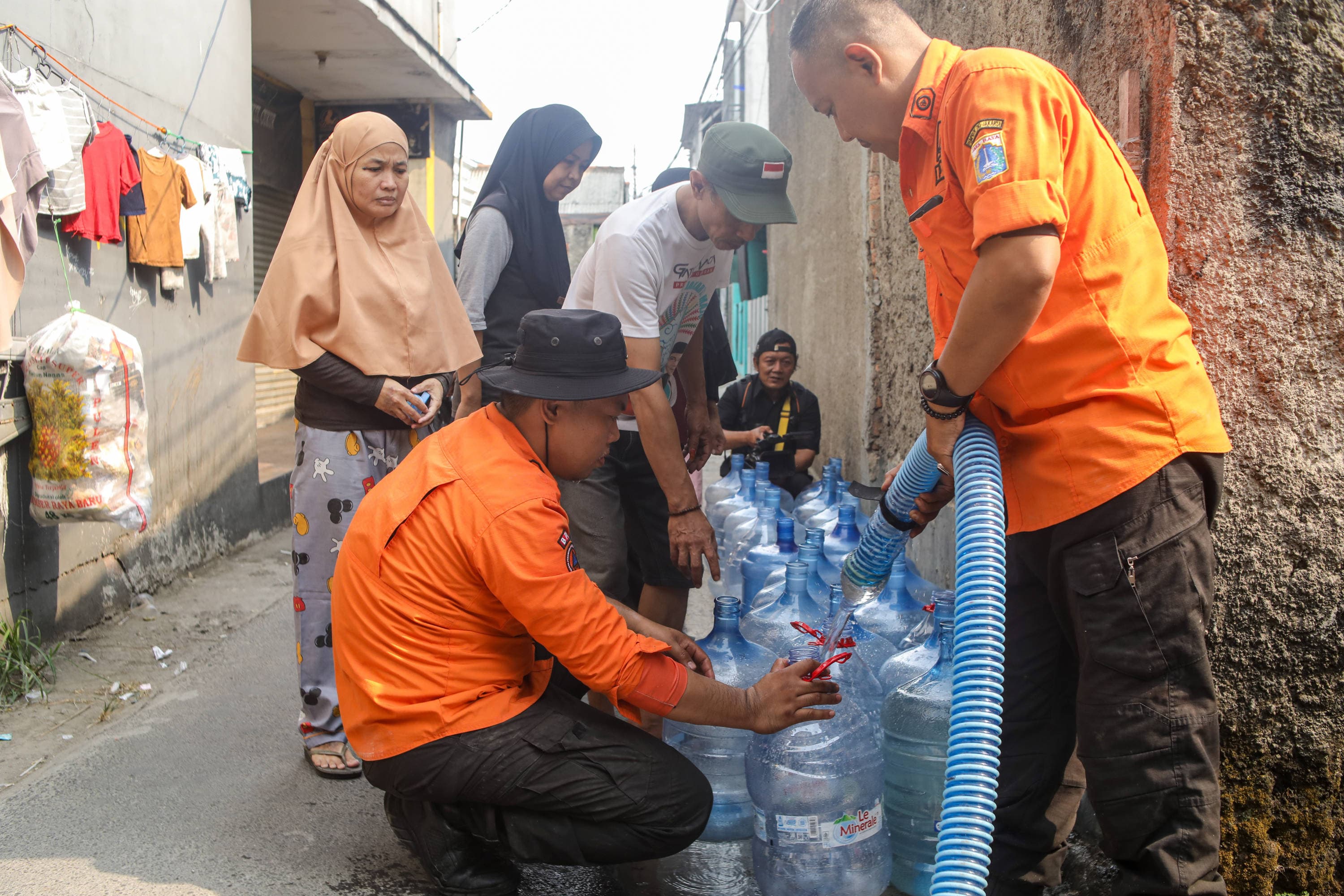 Personel BPBD Jakarta Selatan mengisi air ke dalam wadah milik warga yang terdampak kekeringan di Lenteng Agung, Jakarta, Jumat (18/9/2026). AKURAT.CO/Endra Prakoso
